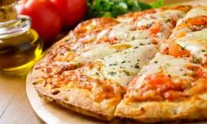 Pizza senza lievito dorata e filante, con pomodoro e mozzarella, accanto a pomodori freschi e olio d'oliva.