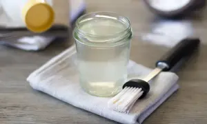 Un bicchiere di bagna per pan di spagna, pronto per inumidire dolci soffici. Accanto, un pennello da pasticceria.