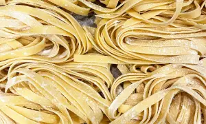 Un primo piano di **tagliatelle fatte in casa**, fresche e spolverate di farina, pronte per essere cucinate.