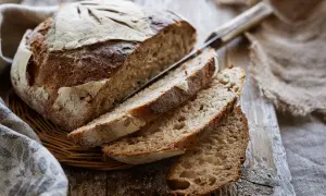 Pane fatto in casa con lievito di birra, tagliato a fette su un tagliere di legno. La crosta è dorata e croccante, l'interno morbido e alveolato.
