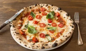 Pizza con lievito madre, pomodorini freschi, mozzarella filante e basilico profumato. Un capolavoro da gustare con coltello e forchetta.
