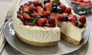 Deliziosa torta fredda allo yogurt, guarnita con fragole, lamponi, mirtilli e una cascata di marmellata. Perfetta per un dessert estivo.