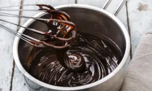 Una frusta mescola una lucida crema al cioccolato in una pentola d'acciaio.