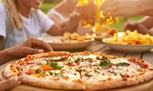 Una deliziosa pizza fatta in casa, tagliata a fette, pronta per essere gustata con amici e birra fresca all'aperto.