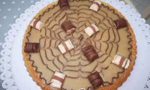 Torta Kinder Bueno con decorazione a ragnatela e pezzi di cioccolato.