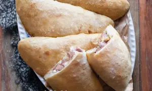 Calzoni al forno dorati e fragranti, ripieni di prosciutto e formaggio filante, pronti per essere gustati.