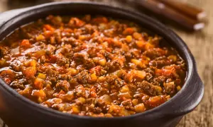 Un saporito ragù di cinghiale in una ciotola di terracotta, pronto per essere gustato con la pasta.