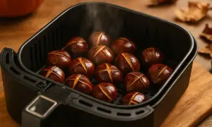 Castagne arrostite nella friggitrice ad aria, con il loro tipico taglio a croce, emanano un leggero vapore.