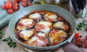 Fette di melanzane cotte in padella con pomodoro e mozzarella filante, un classico piatto di melanzane alla pizzaiola.