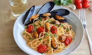 Spaghetti con le cozze e pomodorini, un piatto di mare profumato e colorato, pronto per essere gustato con un bicchiere di vino bianco.