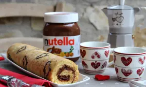 Rotolo alla Nutella pronto per essere gustato, con una moka e due tazze a tema cuore.