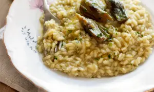 Un cremoso risotto con carciofi freschi, guarnito con prezzemolo tritato e un filo d'olio.