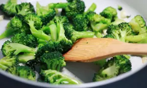 Broccoli in padella, con un mestolo di legno che mescola le cimette verdi e brillanti, pronte per essere gustate.