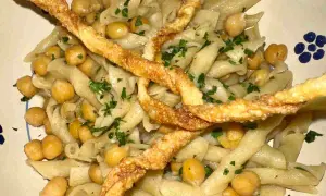 Piatto di ciceri e tria, pasta fresca con ceci e croccanti sfoglie fritte, guarnito con prezzemolo tritato.