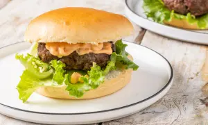Hamburger succulento con salsa, lattuga croccante e panino soffice, preparato in friggitrice ad aria.