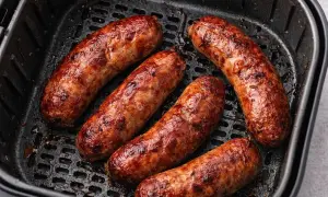 Salsiccia dorata e succulenta in friggitrice ad aria, pronta per essere gustata.