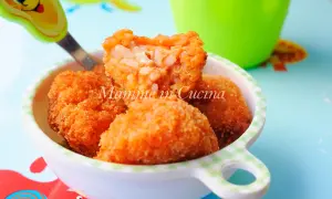 Polpette di riso dorate e croccanti, con un cuore filante di formaggio, servite in una ciotola a quadretti.