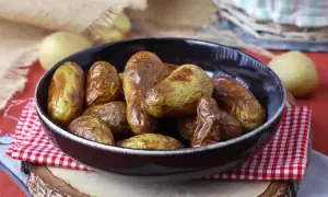 Patate novelle dorate e croccanti, appena sfornate dalla friggitrice ad aria, servite in una ciotola scura.