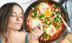 Donna assapora deliziosi uova al pomodoro con formaggio e prezzemolo, servite in padella con pane tostato.