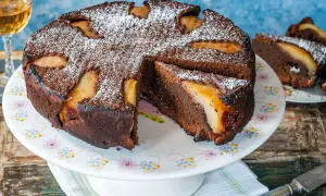 Torta al cioccolato e pere, cotta in friggitrice ad aria, spolverata di zucchero a velo. Una fetta è già servita.