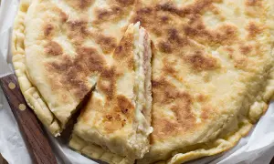 Focaccia in padella dorata e fragrante, farcita con formaggio e salumi, tagliata a spicchi.