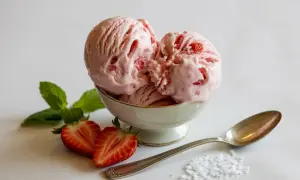 Coppa di cremoso gelato alla fragola, guarnita con fragole fresche e menta.