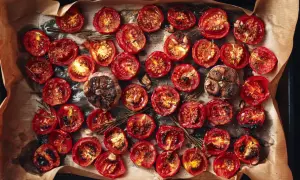 Pomodorini al forno, caramellati e profumati al rosmarino, con teste d'aglio arrostite.