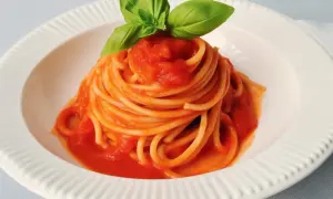 Un piatto di spaghetti al pomodoro fresco, guarnito con foglie di basilico profumato.