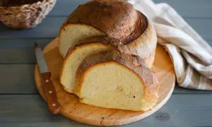 Pane di semola rustico, affettato su tagliere di legno, con coltello e tovagliolo a righe.