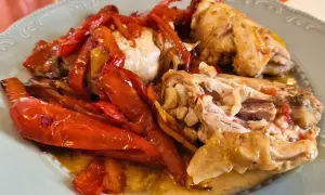 Pollo alla romana succulento con peperoni rossi arrostiti, servito su un piatto chiaro.