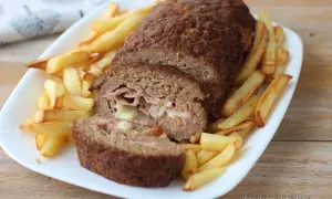 Polpettone ripieno di prosciutto e formaggio, cotto in friggitrice ad aria, servito con patatine fritte croccanti.