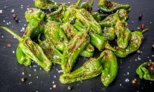 Friggitelli cotti in friggitrice ad aria, cosparsi di sale grosso e pepe nero, con qualche macchia di bruciatura che ne esalta il sapore.