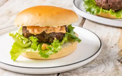 Hamburger succulento con salsa, lattuga croccante e panino soffice, preparato in friggitrice ad aria.