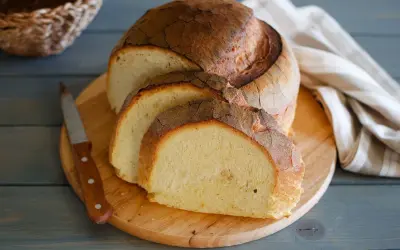 Pane di semola rustico, affettato su tagliere di legno, con coltello e tovagliolo a righe.
