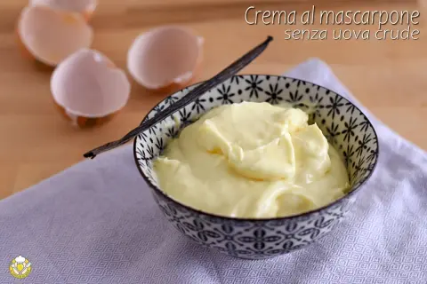 Crema al mascarpone senza uova crude, soffice e vellutata, servita in una ciotola decorata. Guscio d'uovo vuoto sullo sfondo.