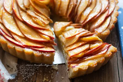 Una fetta di crostata di mele dorata, con mele caramellate disposte a spirale su una base friabile.