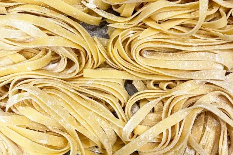 Un primo piano di **tagliatelle fatte in casa**, fresche e spolverate di farina, pronte per essere cucinate.