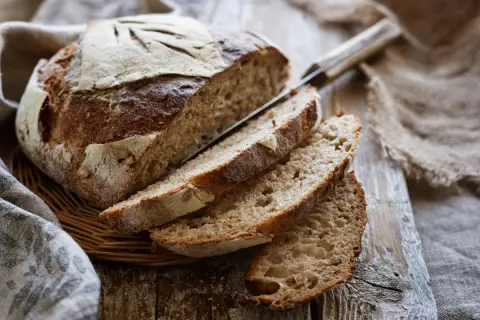 Pane fatto in casa con lievito di birra, tagliato a fette su un tagliere di legno. La crosta è dorata e croccante, l'interno morbido e alveolato.