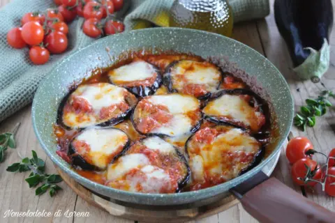 Fette di melanzane cotte in padella con pomodoro e mozzarella filante, un classico piatto di melanzane alla pizzaiola.