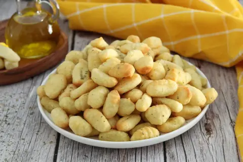 Gnocchi dorati e croccanti, preparati in friggitrice ad aria, conditi con erbe aromatiche.