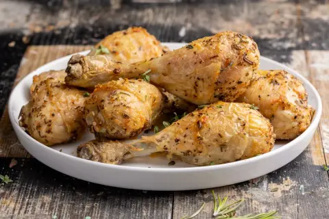 Cosce di pollo dorate e succulente, cotte alla perfezione nella friggitrice ad aria, guarnite con erbe aromatiche fresche.