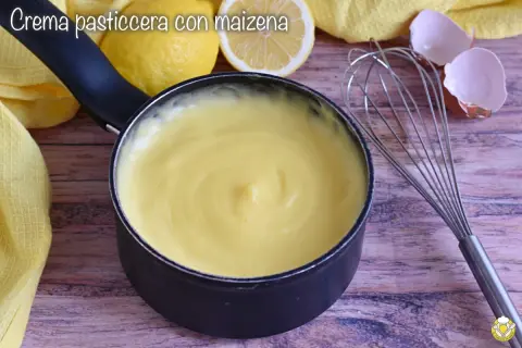 Crema pasticcera liscia e vellutata, preparata con amido di mais, pronta per farcire dolci. Accanto, limoni e frusta.