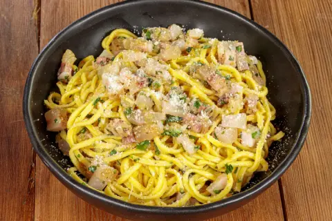 Spaghetti alla chitarra conditi con guanciale croccante, pecorino e prezzemolo fresco, un piatto che sa di tradizione.
