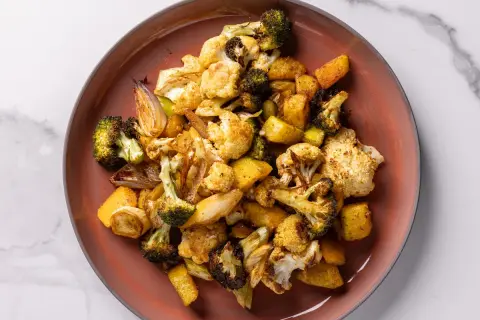 Un piatto di verdure miste, tra cui broccoli, cavolfiore e patate, cotte in friggitrice ad aria, con un aspetto dorato e appetitoso.