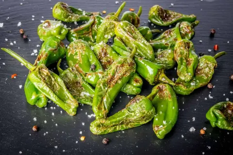Friggitelli cotti in friggitrice ad aria, cosparsi di sale grosso e pepe nero, con qualche macchia di bruciatura che ne esalta il sapore.