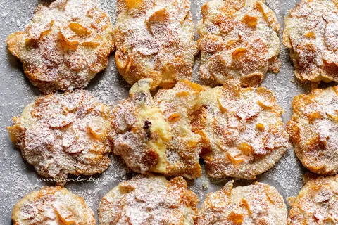 Biscotti croccanti, simili a rose del deserto, ricoperti di zucchero a velo e fiocchi di mais.