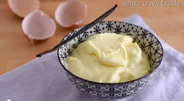 Crema al mascarpone senza uova crude, soffice e vellutata, servita in una ciotola decorata. Guscio d'uovo vuoto sullo sfondo.