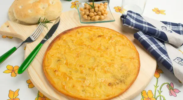 Farinata di ceci in padella, dorata e profumata, pronta per essere gustata con pane fresco e un rametto di rosmarino.