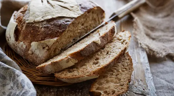 Pane fatto in casa con lievito di birra, tagliato a fette su un tagliere di legno. La crosta è dorata e croccante, l'interno morbido e alveolato.