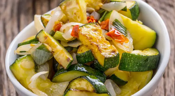 Zucchine in padella, dorate e saporite, con cipolla e pomodoro. Un contorno leggero e gustoso, pronto da gustare.